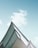 A modern architectural structure with sharp, angular lines and a reflective glass surface set against a bright blue sky with soft clouds.