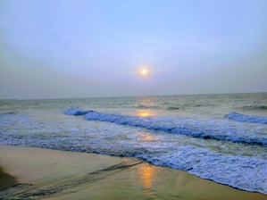 A sunlit beach scene with gentle waves and soft sand, evoking calm and warmth.
