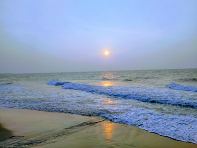 A sunlit beach scene with gentle waves and soft sand, evoking calm and warmth.