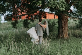 husband carrying his wife walking beside trees