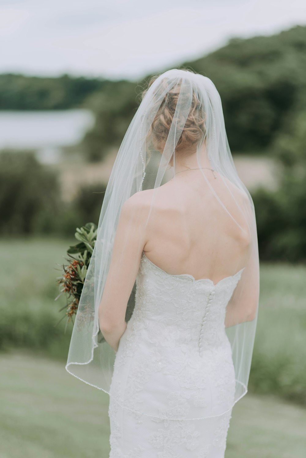 Frau trägt weißes Brautkleid mit Blumenstrauß