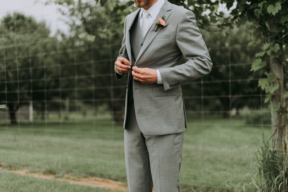 standing man holding his notched lapel suit jacket's button