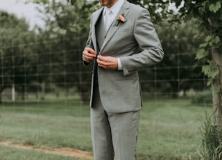 standing man holding his notched lapel suit jacket's button