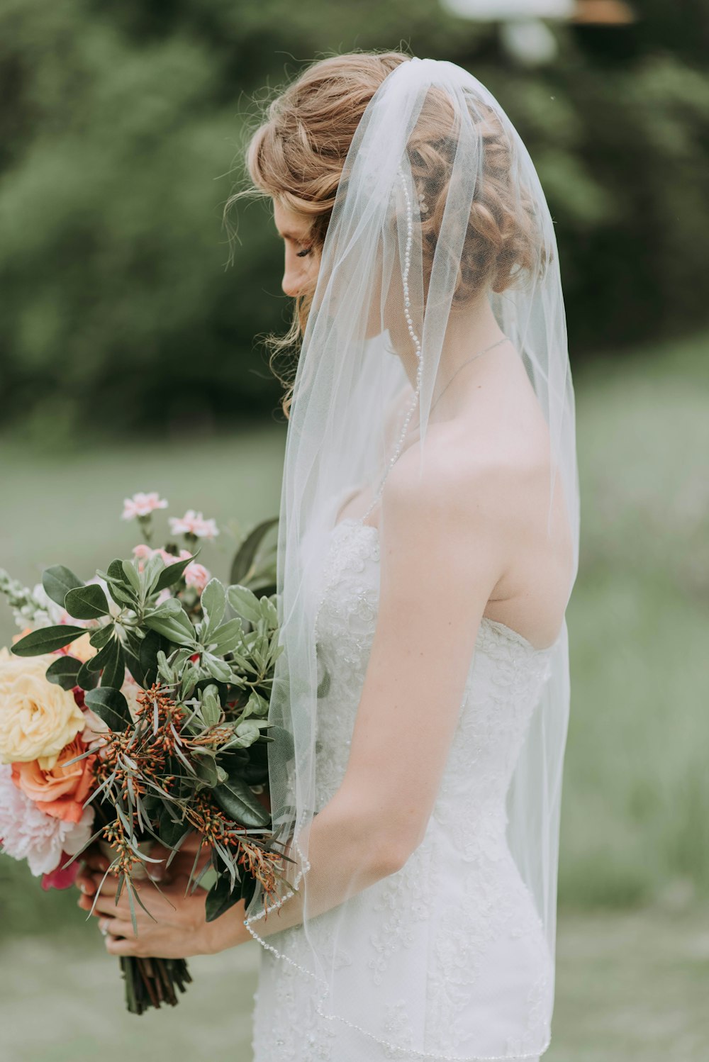 Frau trägt weißes Hochzeitskleid mit Schleier