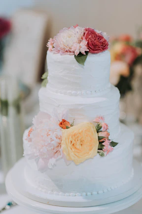 A beautifully decorated three-milk cake with fresh flowers on top, perfect for a wedding celebration.