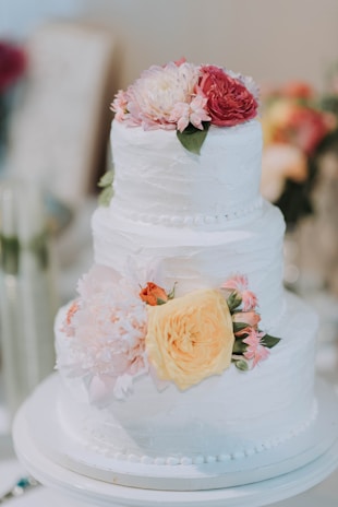 An elegant tiered cake with soft pastel layers and fresh flowers arranged on top.