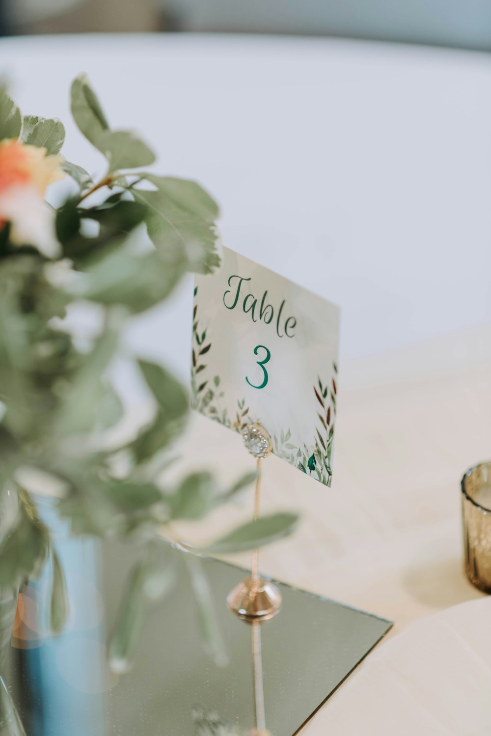 un numéro de table sur une table avec un vase de fleurs