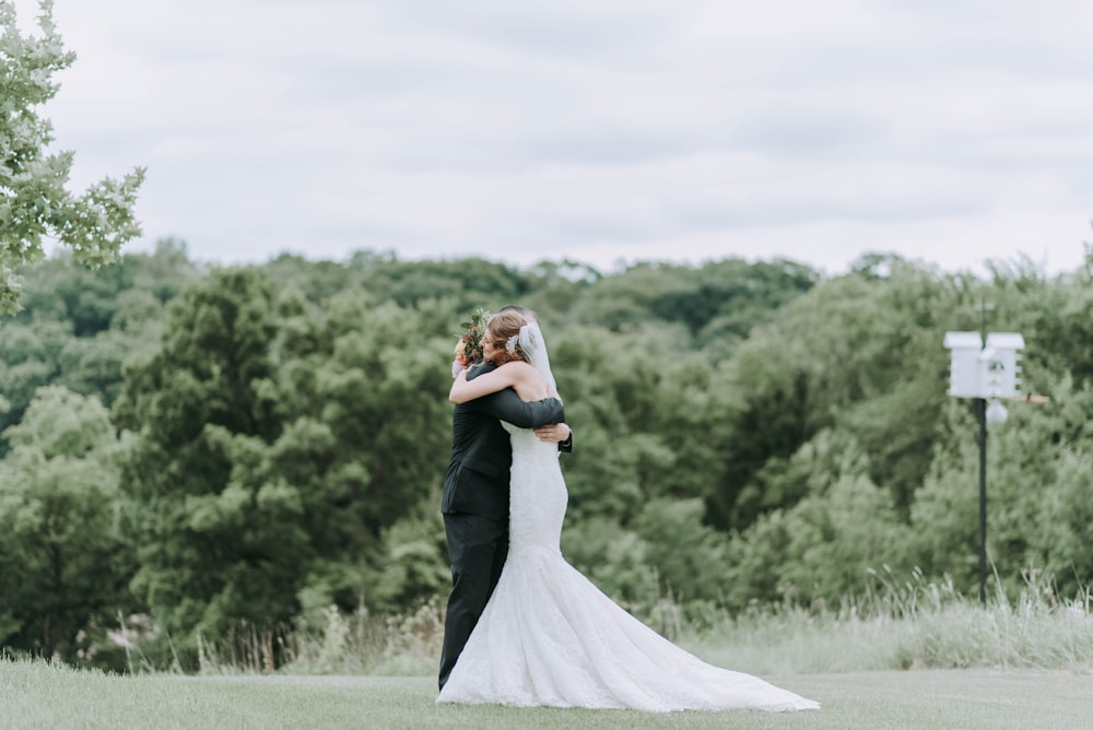 woman hugging man standing on green grass field