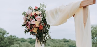 bouquet of assorted-color flowers hanged on brown plank with white textile