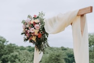 bouquet of assorted-color flowers hanged on brown plank with white textile