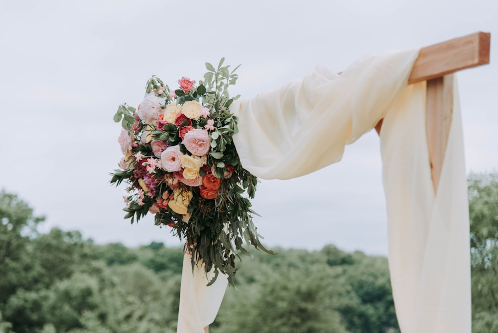 Bouquet di fiori di colori assortiti appesi su tavola marrone con tessuto bianco