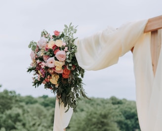 bouquet of assorted-color flowers hanged on brown plank with white textile