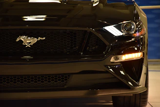 Close-up shot of a sleek front splitter on a black Ford Mustang under moody lighting.