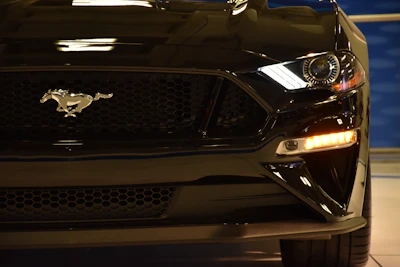 Close-up shot of a sleek front splitter on a black Ford Mustang under moody lighting.