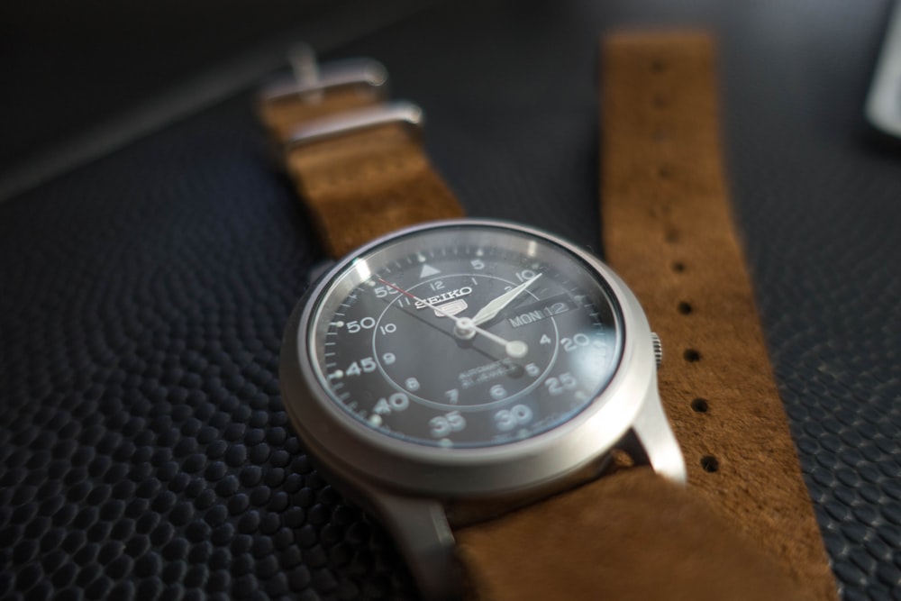 round silver-colored analog watch with brown leather band