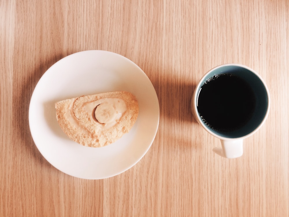 mug full of black coffee near a slice of cake