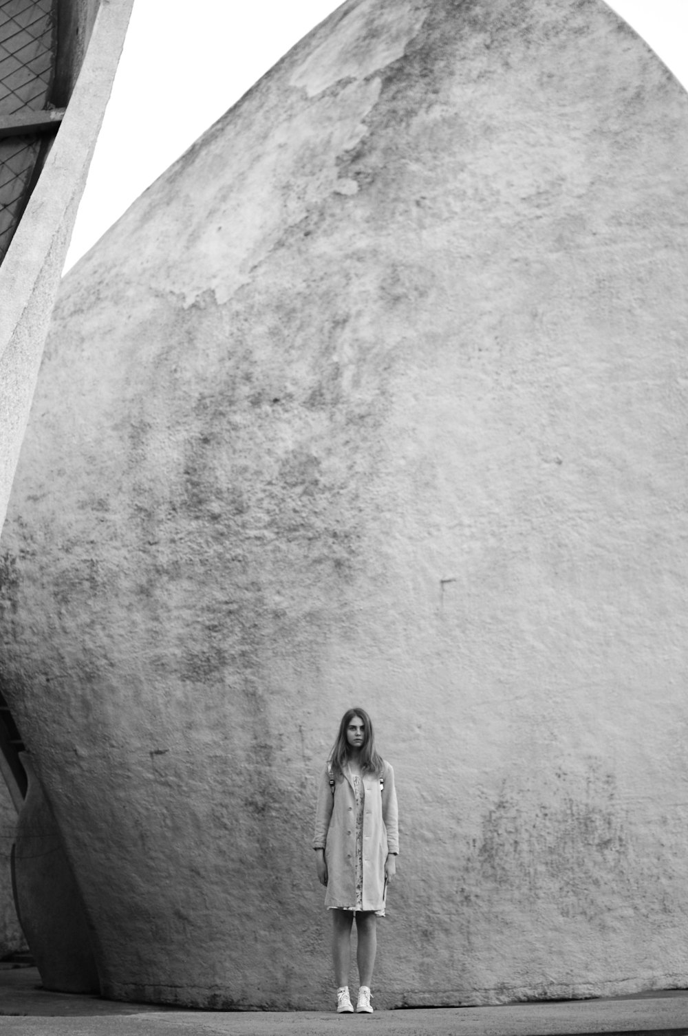 grayscale photo of woman standing near building