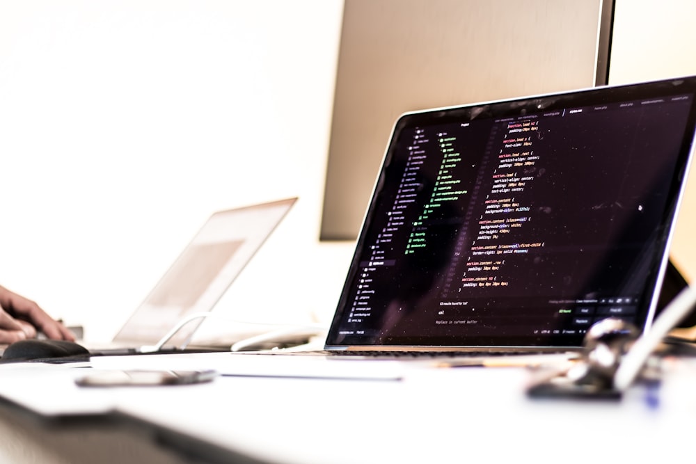 black laptop computer turned-on displaying source code on table