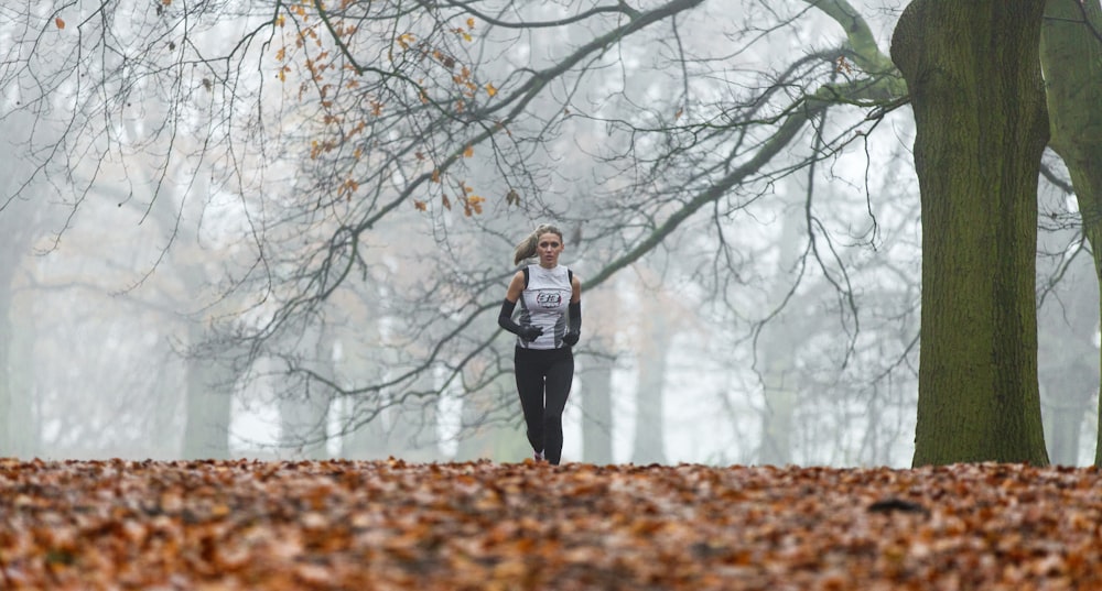 running woman under bare tree during daytime