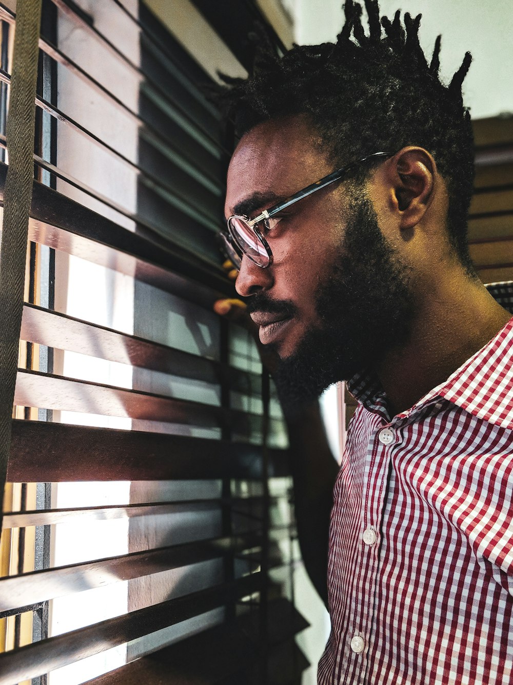 man looking through the window blind inside room