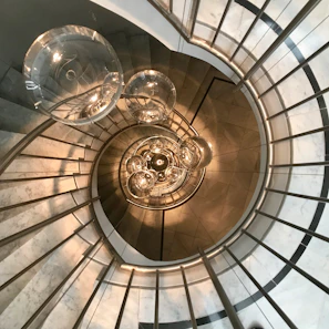 Close-up of a sleek spiral metal staircase with a polished stainless steel handrail in a modern home setting