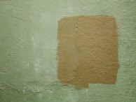 Before and after shots of a repaired drywall patch in a living room.
