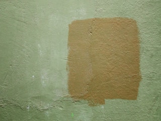 Technician patching and painting a freshly prepped apartment wall.