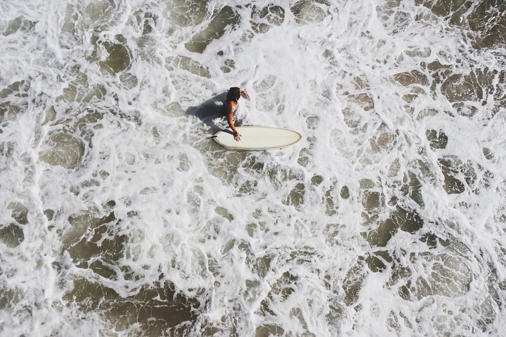 person in body of water holding surfboard