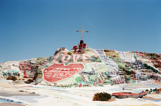 assorted-color land formation with cross on top in Salvation Mountain United States