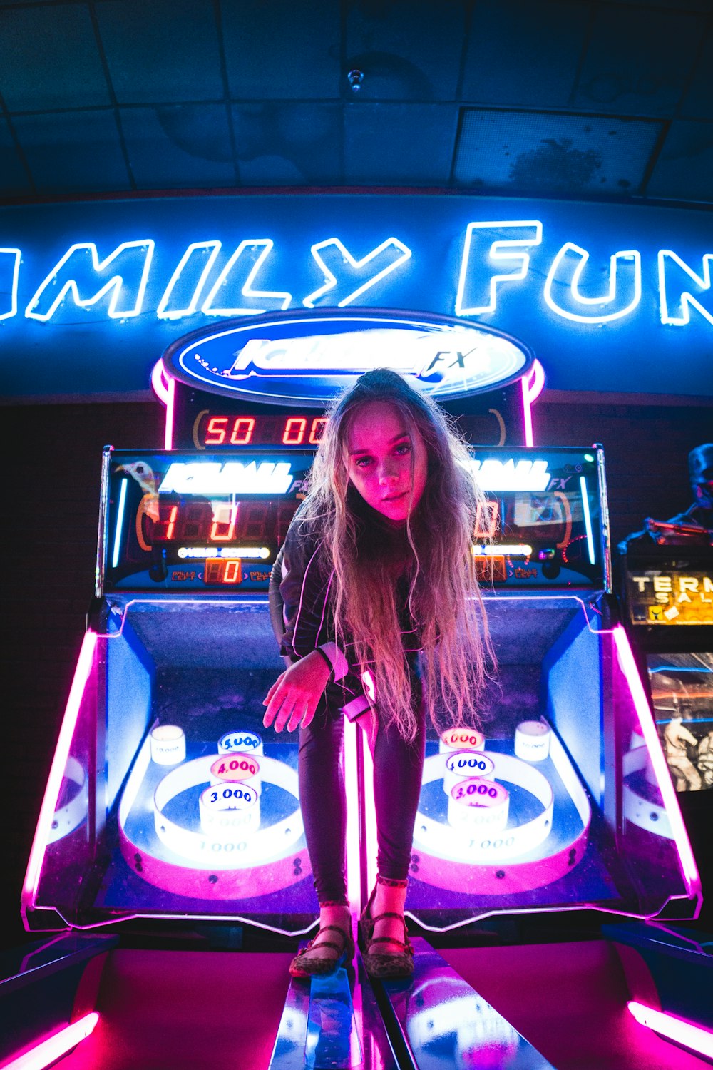 Frau sitzt auf schwarz-lila Arcade-Spielautomat