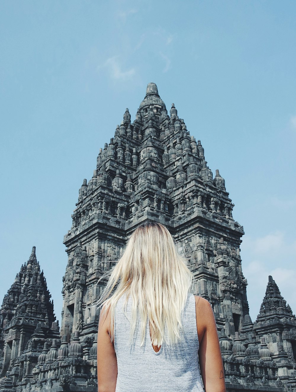 mujer de pelo rubio de pie frente al templo de hormigón