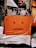 Layered posters on a wall include an advertisement featuring two people in casual, colorful clothing, with one person lying on a wooden deck. Below, an abstract poster depicts a minimalist orange face with a neutral expression, composed of simple red shapes.