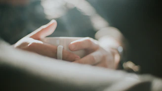 Close-up of a hand holding a warm beige mug with a minimalist background.