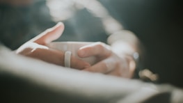 Hands holding a warm mug against a soft knitted blanket background.