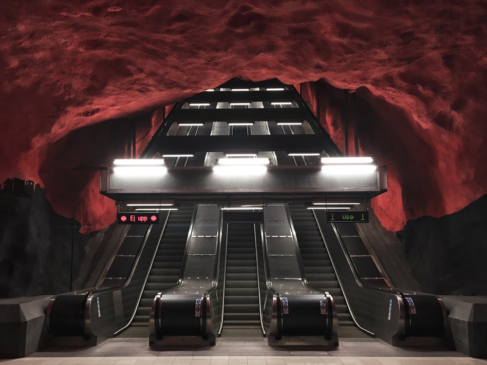 three black escalators inside red and black room