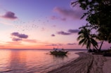 A sunset view over Cancun’s turquoise waters with a small boat in the distance.