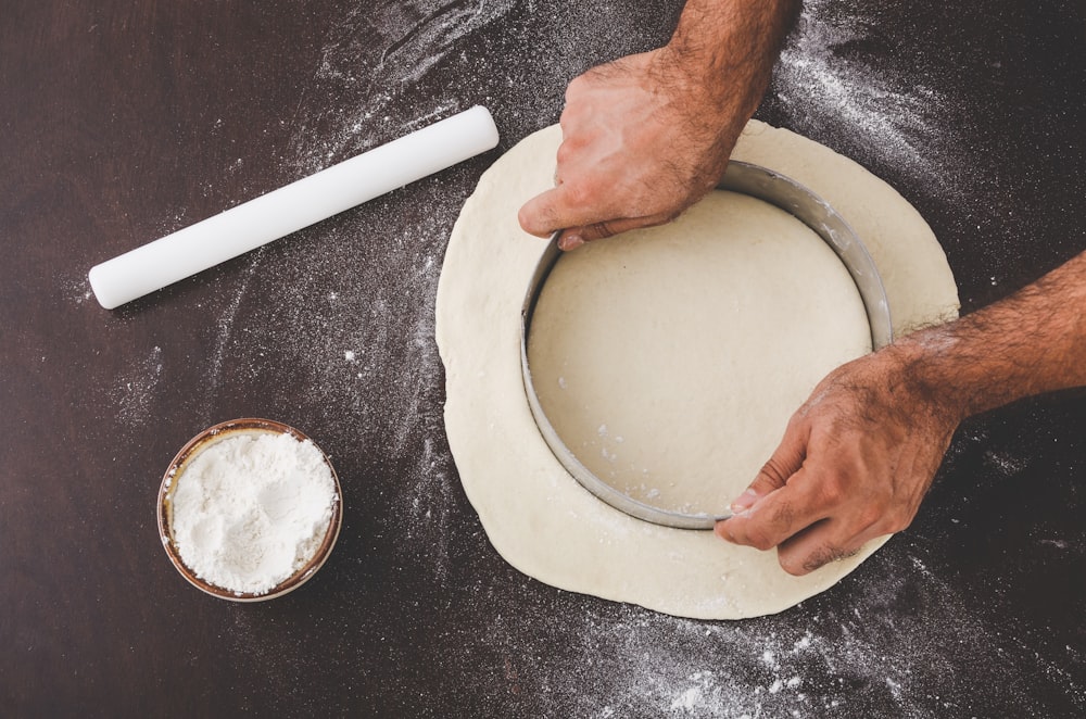 person cutting dough with round cutter