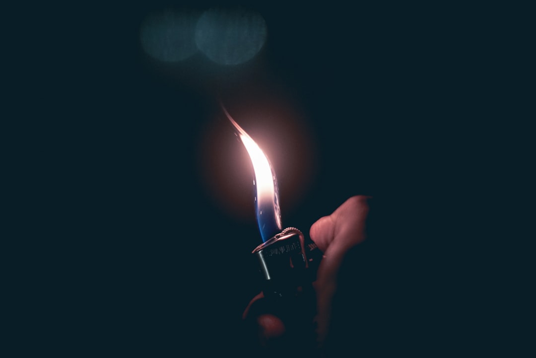 person holding lit lighter at dark room