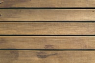 Wooden planks aligned horizontally, exhibiting natural textures and grain patterns, with a weathered and slightly rustic appearance.