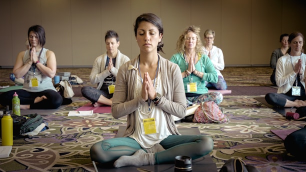A serene group of professionals smiling gently during a meditation session in a sunlit Pune studio.