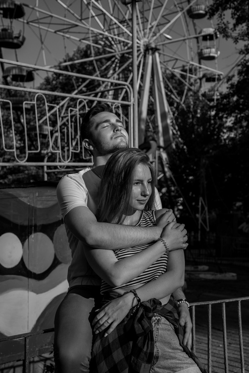 grayscale photo of man hugging woman near Ferri's wheel