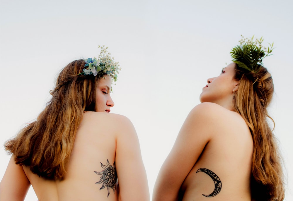 two naked women with sun and crescent moon tattoos