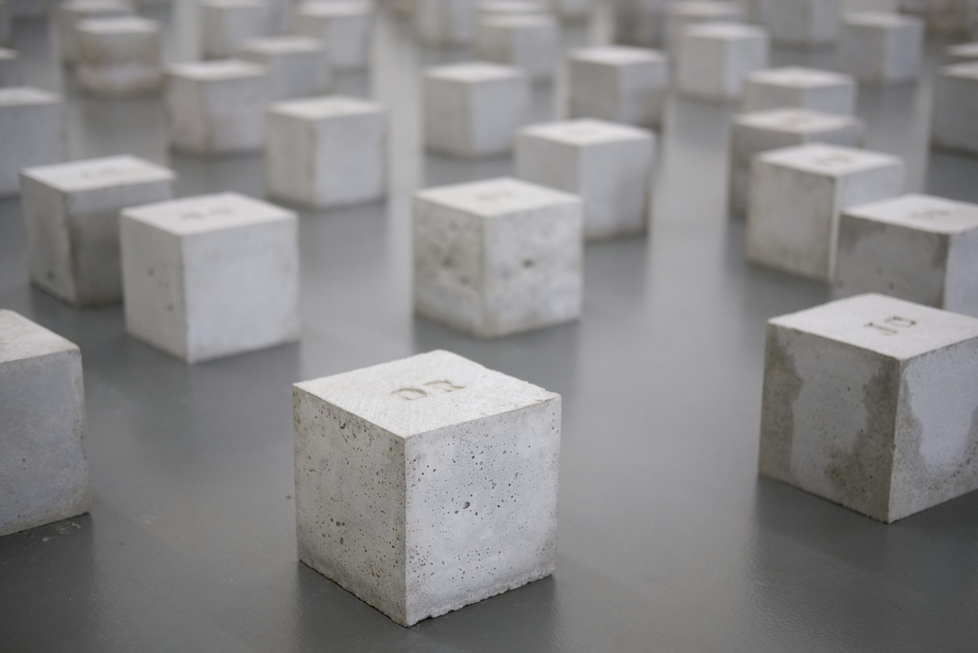 A series of identical white cubes, seemingly made from concrete or a similar material.
