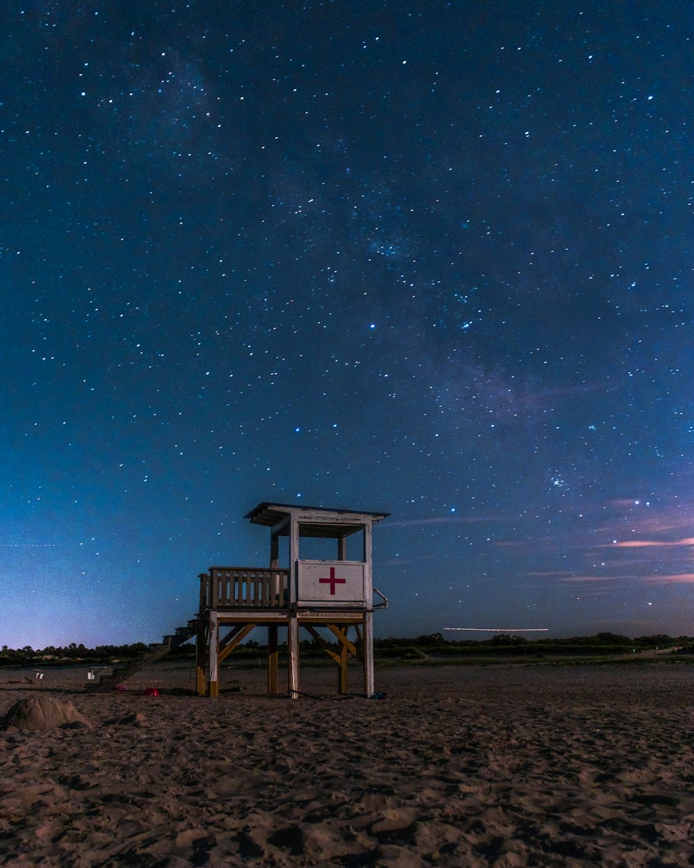 white lifeguard shed on beach under starry sky