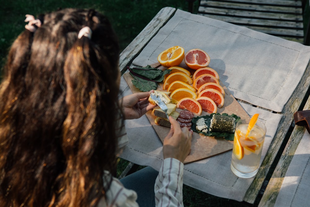 person holding slice fruits near gray wooden table close-up photo