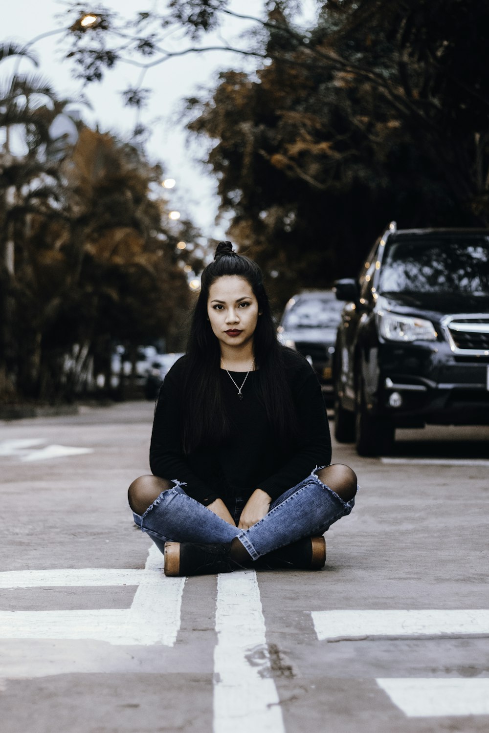 focus photography of woman sitting on gray concrete road during daytime