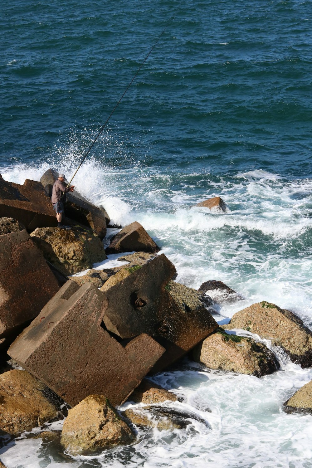 uomo che pesca vicino alla spiaggia durante il giorno