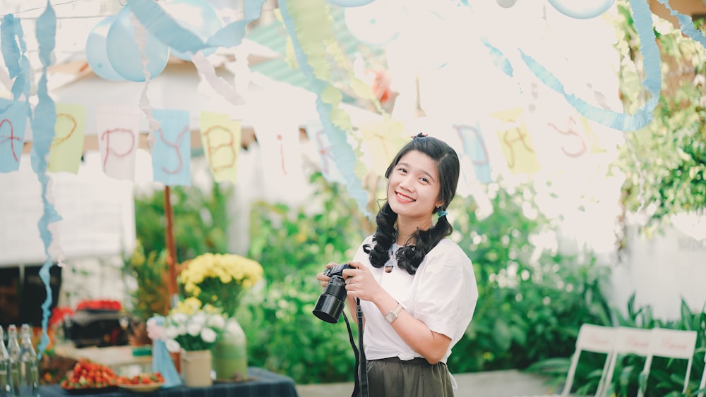 woman in white blouse holding black DSLR camera