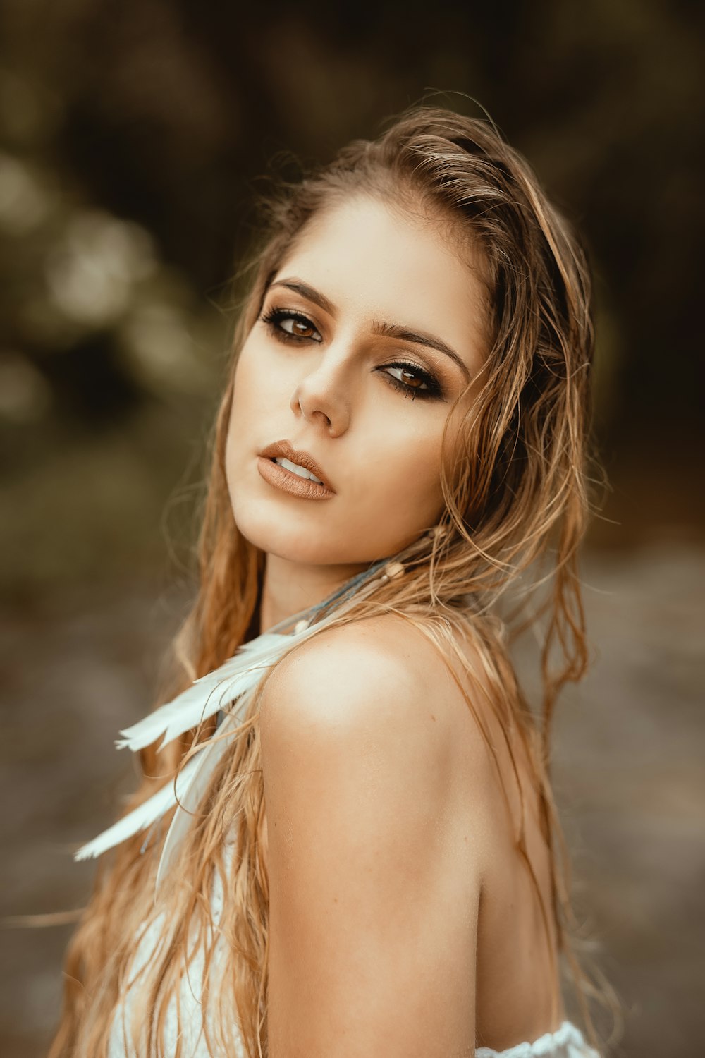 focus photography of blonde woman with feather earring