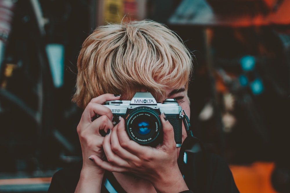 person holding gray and black Minolta SLR camera